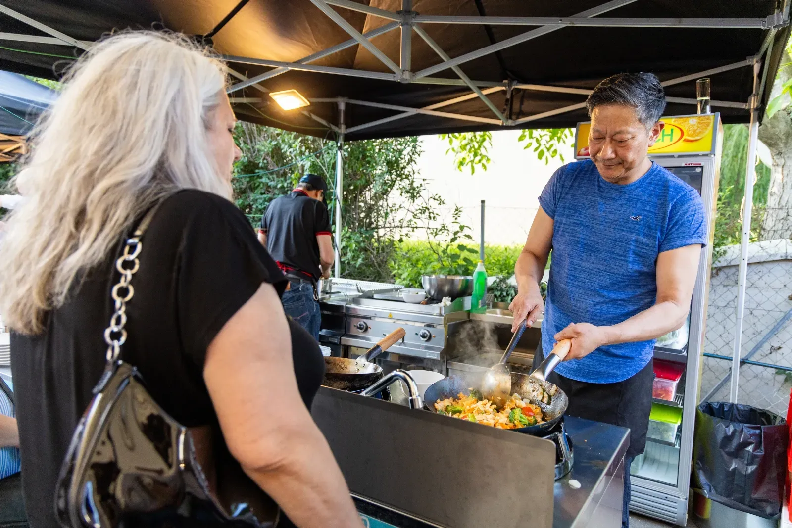 Am Foodtruck wird frisch in der Pfanne gekocht, davor wartet ein Gast