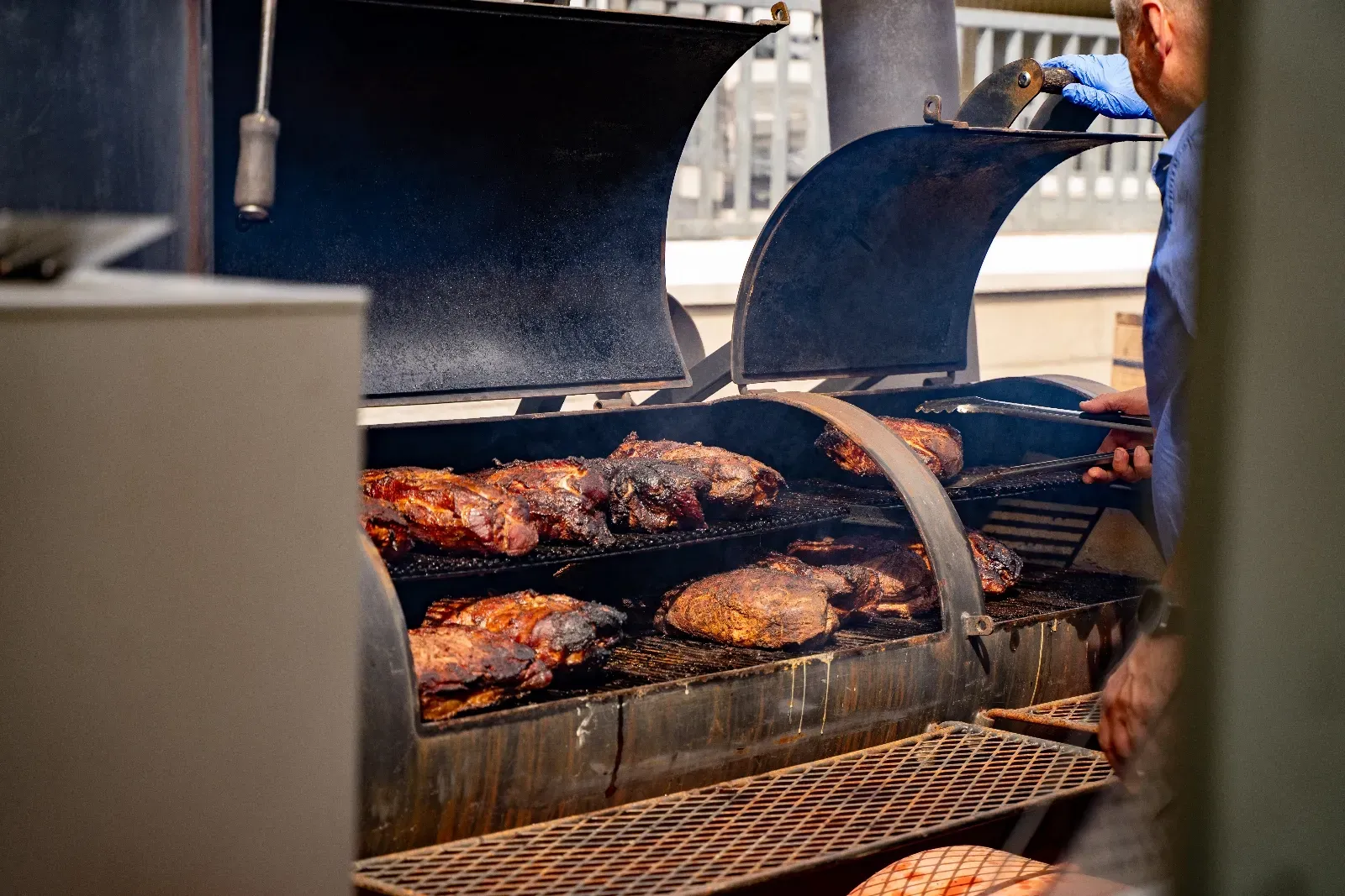 Geöffneter Smoker mit Fleischstücken auf dem Rost